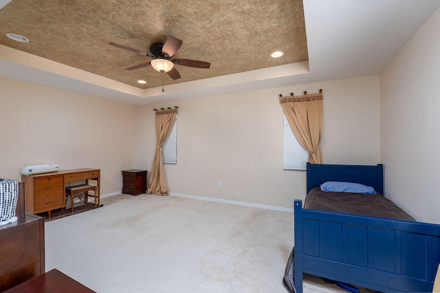 bedroom with light colored carpet, a raised ceiling, ceiling fan, and multiple windows