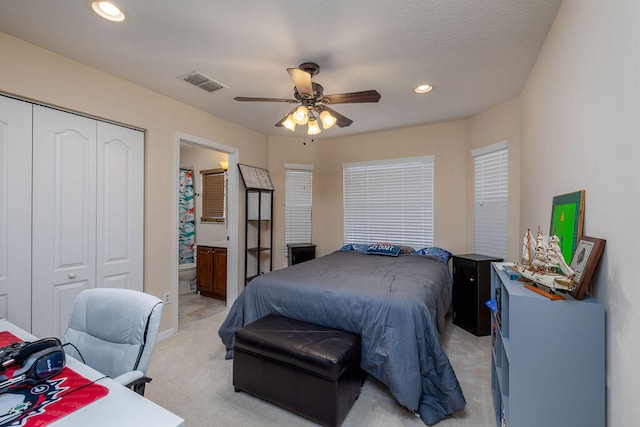 carpeted bedroom with a closet, ensuite bath, and ceiling fan