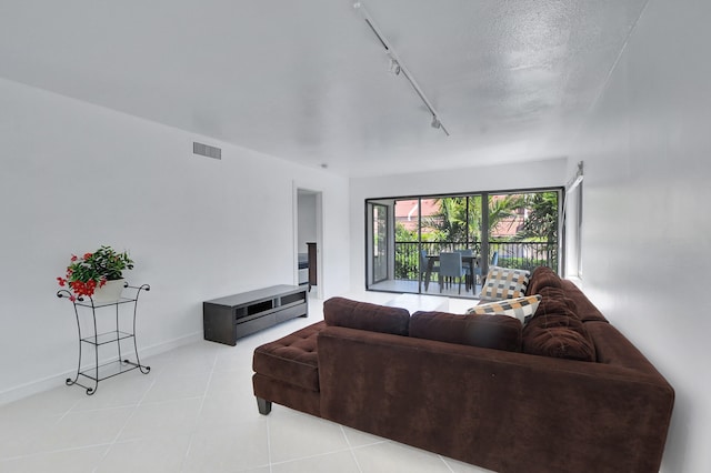 living room with rail lighting, a textured ceiling, and light tile floors