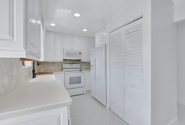 kitchen with light tile floors, white cabinets, sink, white appliances, and backsplash