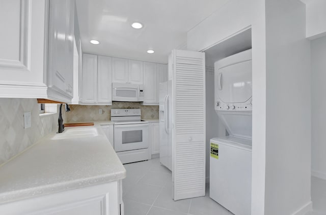 kitchen featuring white cabinets, white appliances, stacked washer and clothes dryer, backsplash, and sink