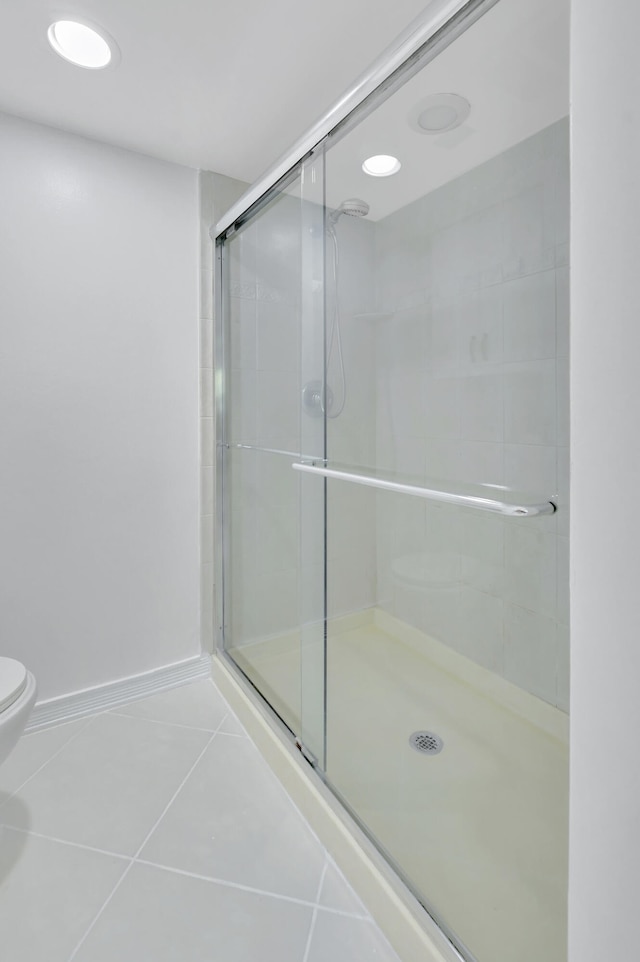 bathroom with walk in shower, toilet, and tile flooring