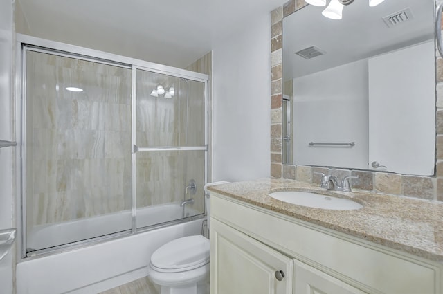 full bathroom featuring toilet, large vanity, and bath / shower combo with glass door