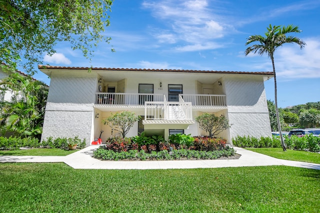 view of front of home with a balcony and a front yard