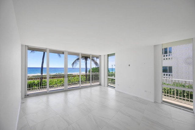 spare room with floor to ceiling windows, plenty of natural light, and a water view