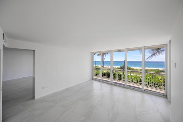 empty room featuring a water view and a wall of windows