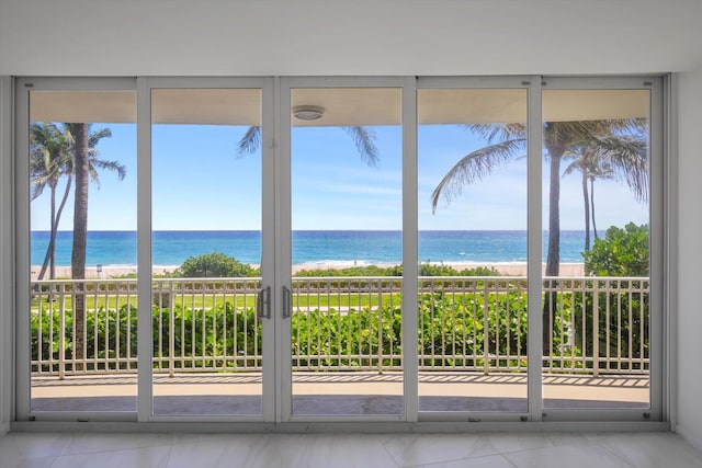 unfurnished sunroom featuring a water view, a wealth of natural light, and a beach view