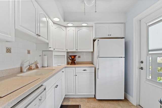 kitchen with sink, backsplash, white cabinets, and white appliances