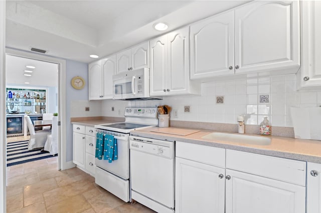 kitchen featuring sink, white appliances, white cabinets, and backsplash