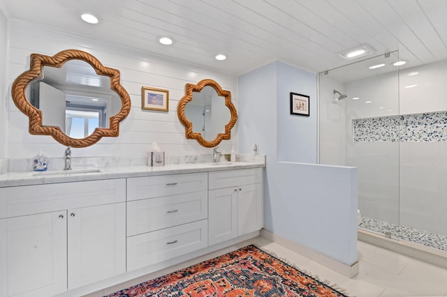 bathroom with tile patterned flooring, vanity, and a tile shower