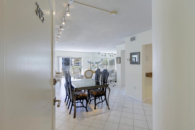 tiled dining room with rail lighting and a textured ceiling