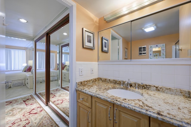 bathroom with tile floors, vanity, tile walls, backsplash, and a shower with shower door