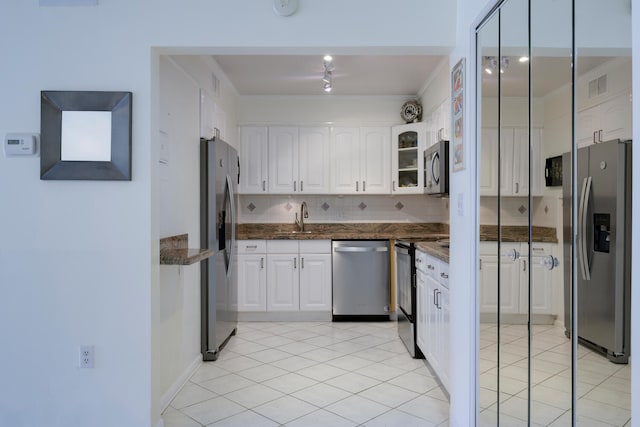 kitchen featuring appliances with stainless steel finishes, tasteful backsplash, dark stone countertops, white cabinets, and sink