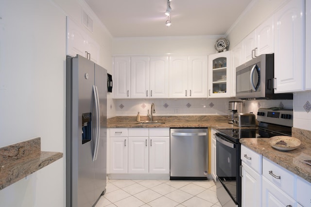 kitchen with white cabinets, light stone countertops, appliances with stainless steel finishes, light tile floors, and sink