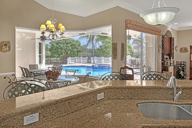 kitchen featuring hanging light fixtures, light stone counters, sink, an inviting chandelier, and ornamental molding