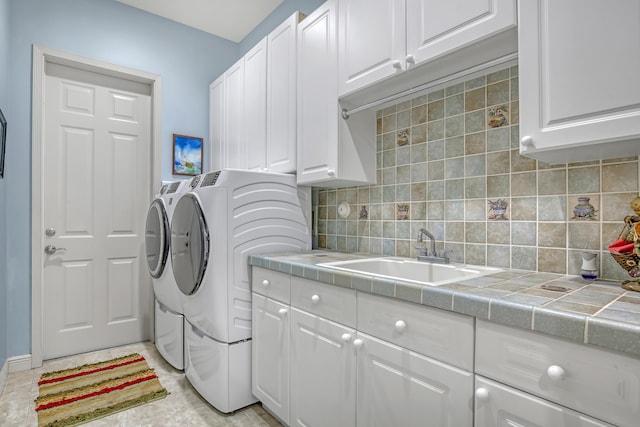 laundry room with cabinets, sink, light tile flooring, and washing machine and clothes dryer