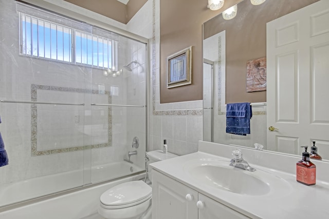 full bathroom featuring vanity, toilet, tile walls, and bath / shower combo with glass door