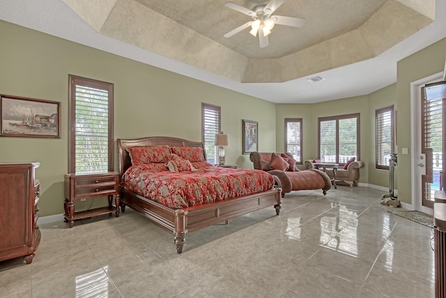 bedroom with ceiling fan, light tile flooring, a raised ceiling, and multiple windows