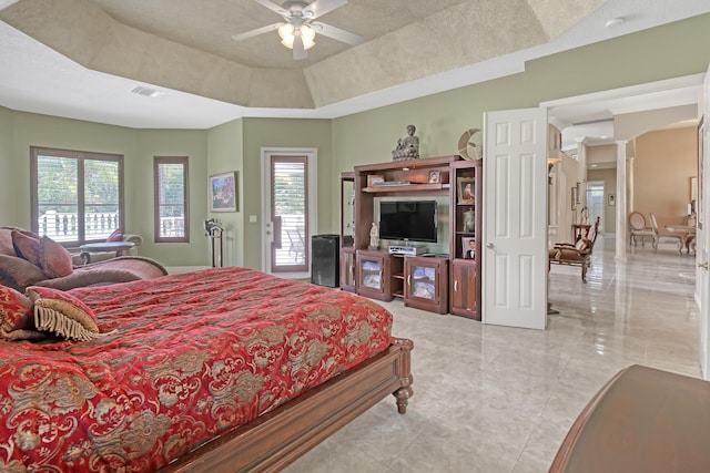 tiled bedroom featuring a raised ceiling, ceiling fan, access to exterior, and multiple windows