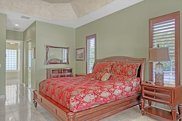 bedroom with light tile floors and a tray ceiling