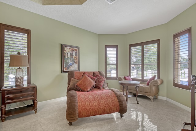 living area with a textured ceiling and light tile floors