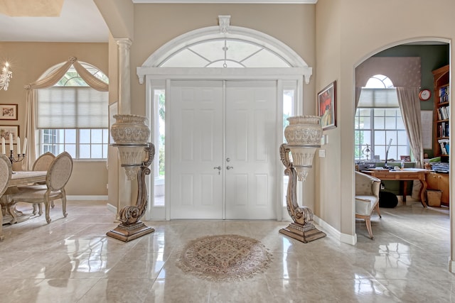 tiled entrance foyer with a high ceiling and decorative columns