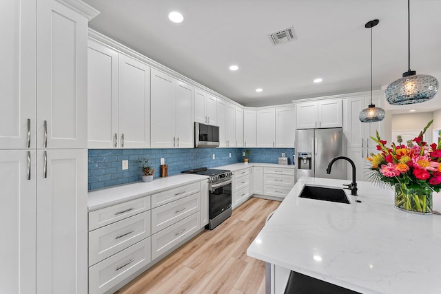 kitchen with pendant lighting, sink, appliances with stainless steel finishes, white cabinetry, and decorative backsplash