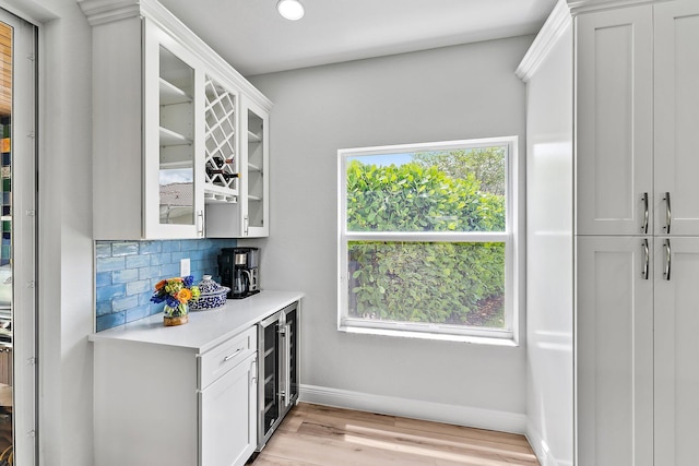 bar with a healthy amount of sunlight, backsplash, and white cabinets