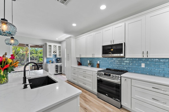 kitchen featuring wine cooler, sink, white cabinetry, appliances with stainless steel finishes, and pendant lighting