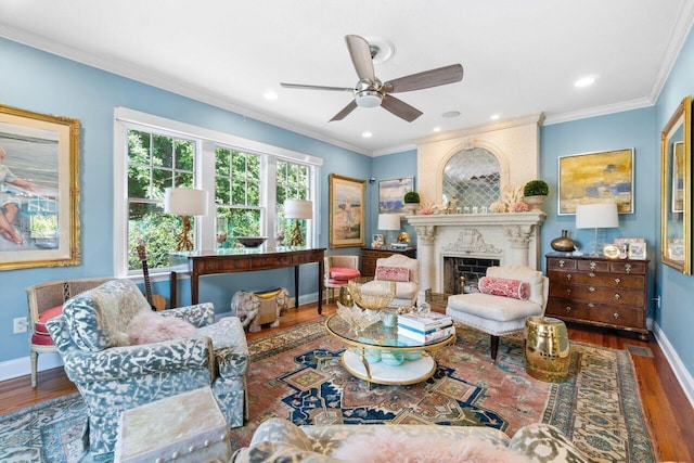 living room with ceiling fan, a large fireplace, dark hardwood / wood-style floors, and crown molding