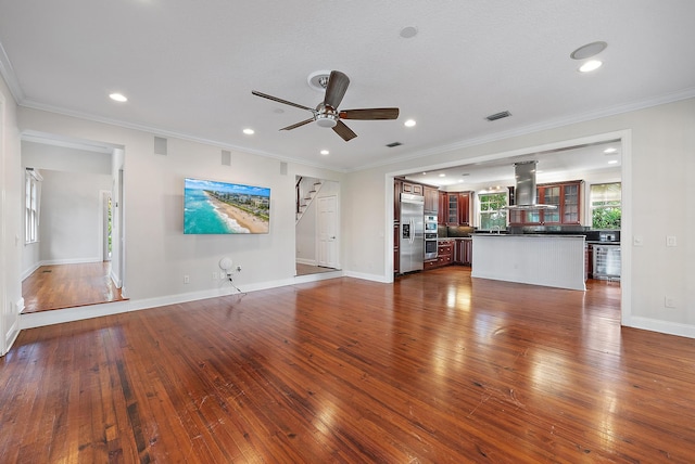 unfurnished living room featuring dark wood-type flooring, ceiling fan, and crown molding