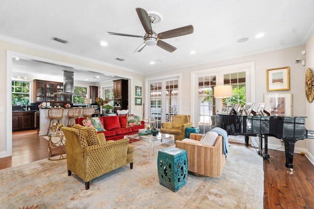 living room with ceiling fan, a healthy amount of sunlight, light hardwood / wood-style flooring, and ornamental molding