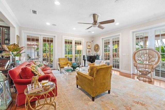 living room with ornamental molding, french doors, light hardwood / wood-style floors, and a textured ceiling