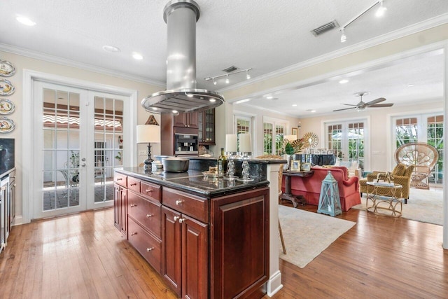 kitchen with light wood-type flooring, a textured ceiling, a kitchen island, and french doors