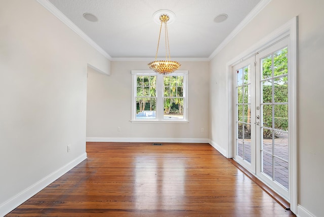 unfurnished dining area featuring a textured ceiling, wood-type flooring, french doors, and crown molding