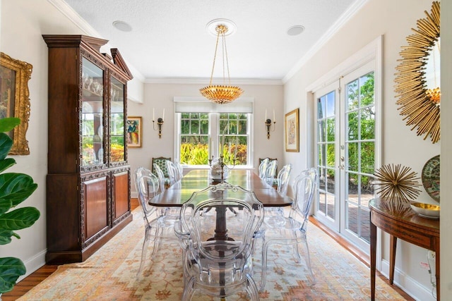 dining space with french doors, light wood-type flooring, a textured ceiling, and crown molding