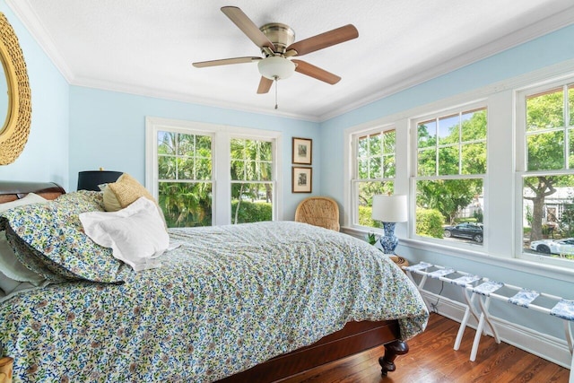 bedroom featuring ornamental molding, multiple windows, hardwood / wood-style flooring, and ceiling fan