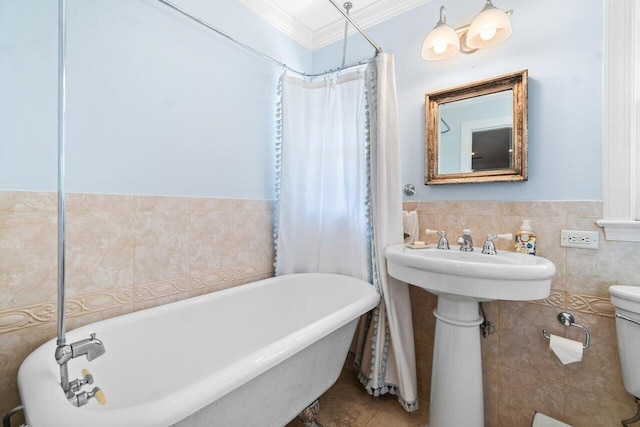 bathroom featuring tile patterned flooring, crown molding, toilet, a bathtub, and tile walls