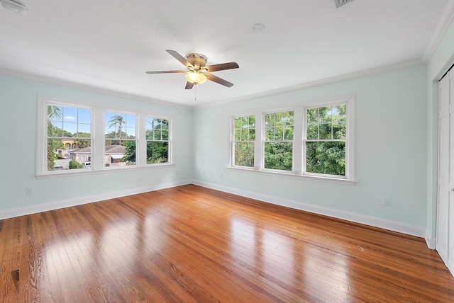 unfurnished room with plenty of natural light, hardwood / wood-style flooring, crown molding, and ceiling fan