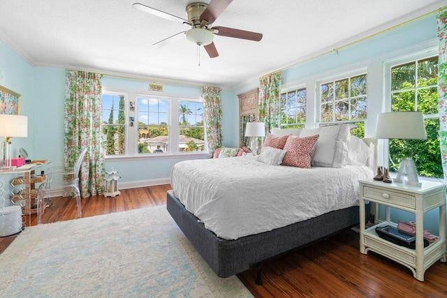 bedroom featuring crown molding, dark hardwood / wood-style flooring, multiple windows, and ceiling fan