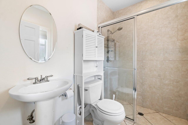 bathroom with toilet, tile patterned floors, and a shower with shower door