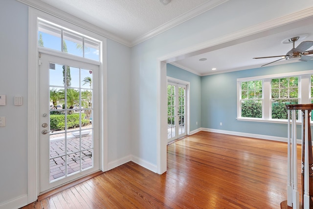 interior space with ceiling fan, wood-type flooring, a textured ceiling, and ornamental molding