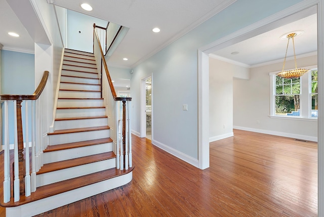 stairs featuring ornamental molding and hardwood / wood-style flooring