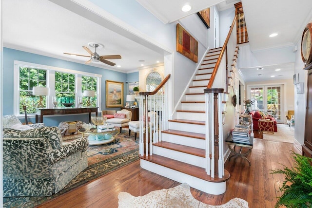 stairway with hardwood / wood-style floors, ceiling fan, and ornamental molding