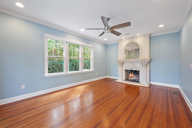 unfurnished living room with ceiling fan, hardwood / wood-style flooring, a large fireplace, and crown molding