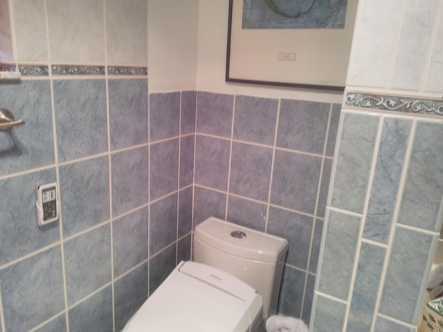 bathroom with tile walls and toilet