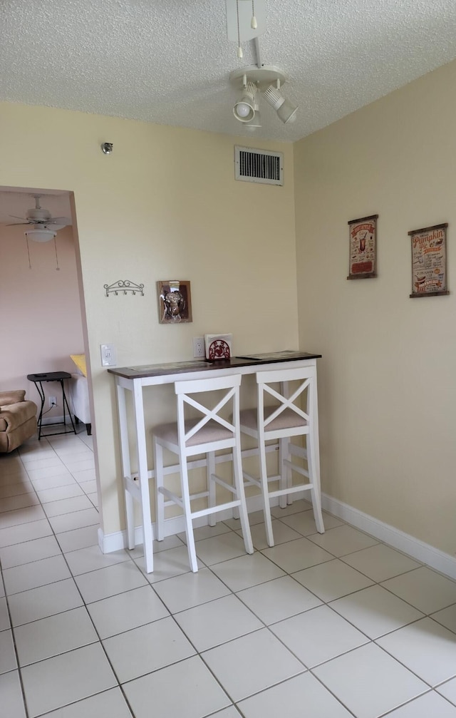 unfurnished dining area with light tile patterned floors, a textured ceiling, and ceiling fan