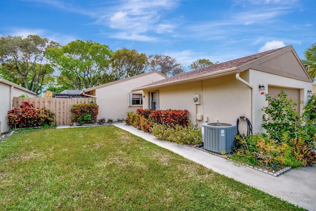 view of property exterior featuring a garage, a lawn, and central air condition unit