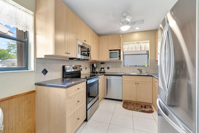 kitchen with light brown cabinets, sink, stainless steel appliances, decorative backsplash, and light tile patterned floors