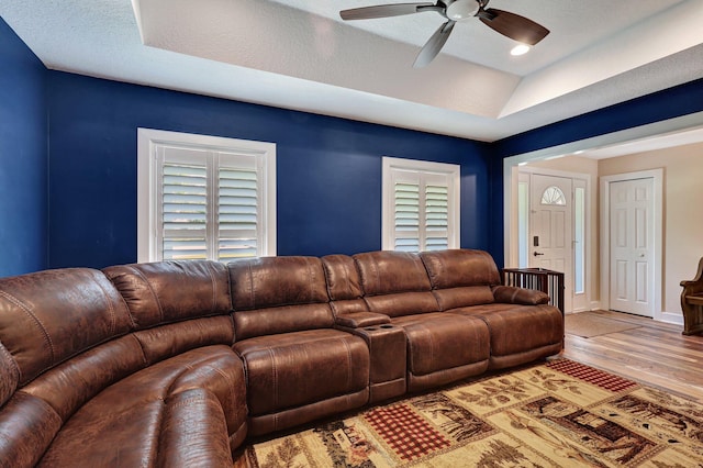 living room with a raised ceiling, ceiling fan, a textured ceiling, and hardwood / wood-style flooring